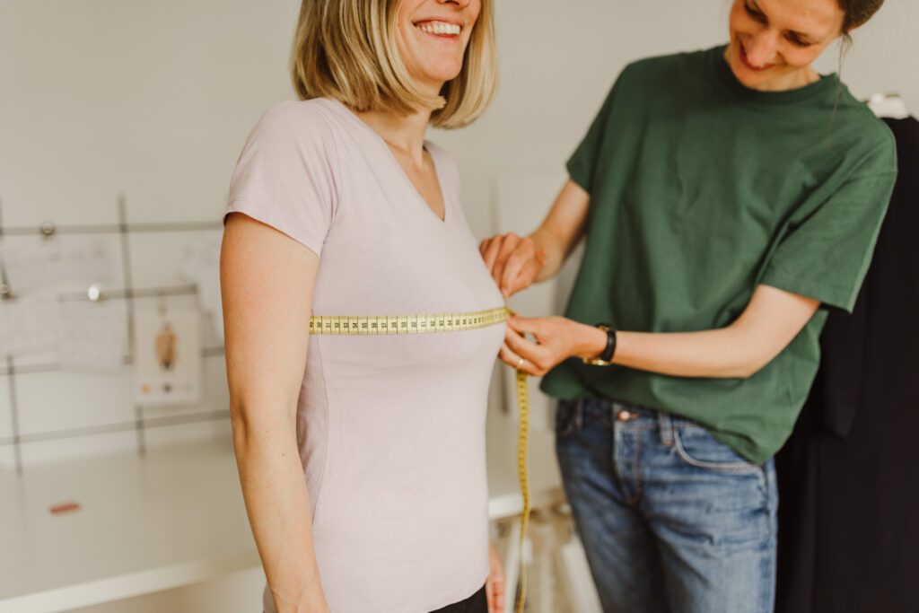 Anna misst den Brustumfang bei einer anderen Frau
